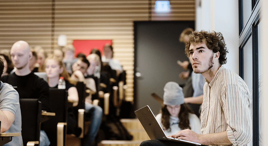 Mandlig studerende sidder koncentreret om undervisningen med sin computer